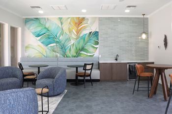 A modern living room with a large mural of tropical leaves on the wall.